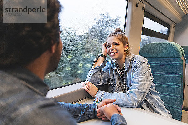 Porträt einer lächelnden jungen Frau  die mit ihrem Freund im Zug reist  London  UK