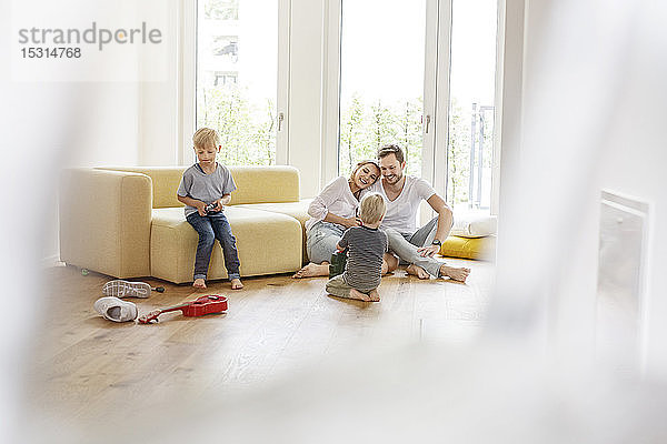 Glückliche Familie mit zwei Söhnen  die im Wohnzimmer ihres neuen Zuhauses spielen