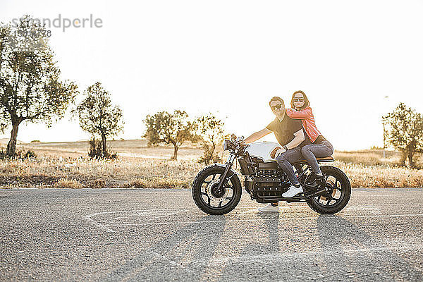 Porträt eines Paares  das in der Abenddämmerung auf einem Motorrad sitzt
