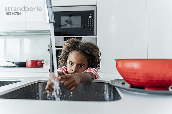 Mädchen wäscht sich die Hände an der Küchenspüle