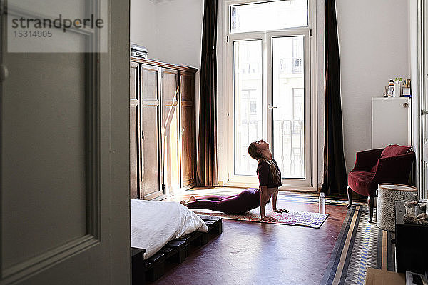 Junge brünette Frau praktiziert Yoga im Studentenwohnheim