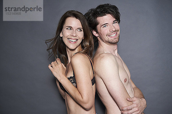 Porträt eines glücklichen  halb bekleideten Paares Rücken an Rücken