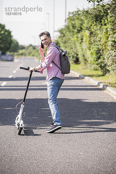 Geschäftsmann benutzt Smartphone  schiebt seinen E-Scooter