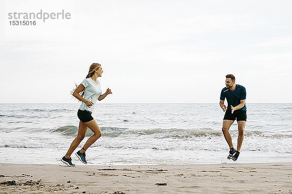 Joggerin mit ihrem Trainer am Strand