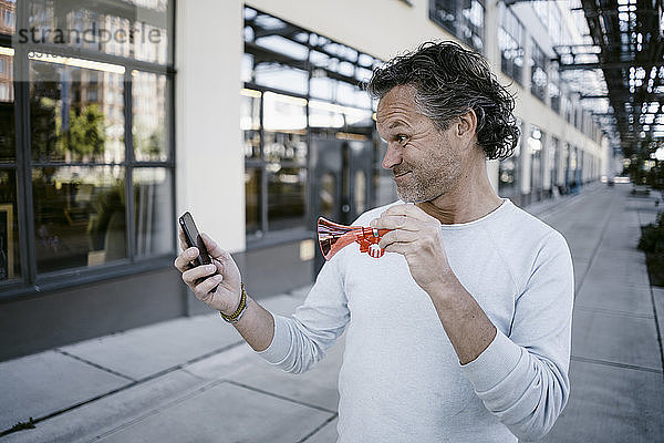Porträt eines reifen Mannes mit Horn und Smartphone