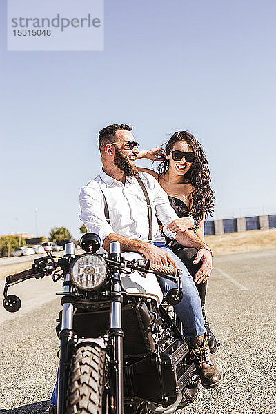 Porträt von lachendem Paar auf Motorrad sitzend