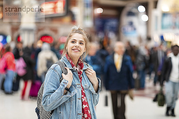 Lächelnde junge Frau am Bahnhof
