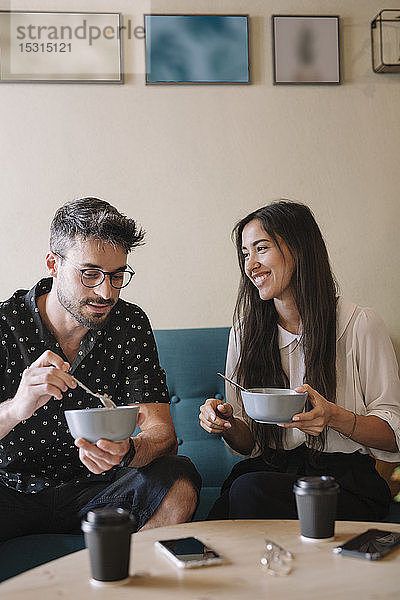 Junges Paar sitzt auf einer Couch in einem Café und frühstückt