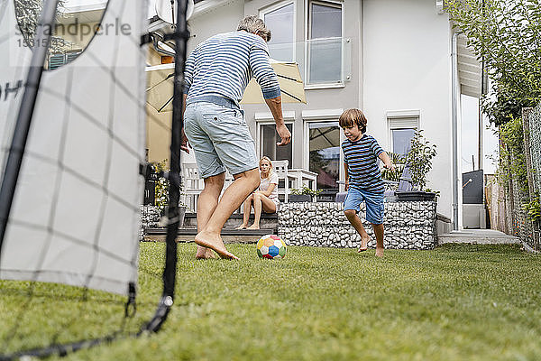 Vater und Sohn spielen im Garten Fussball