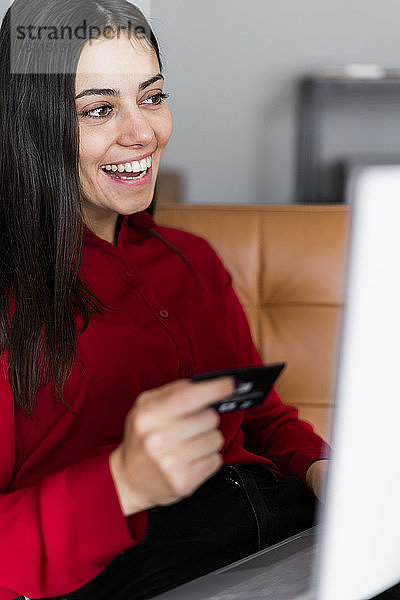 Glückliche junge Frau zu Hause beim Online-Shopping