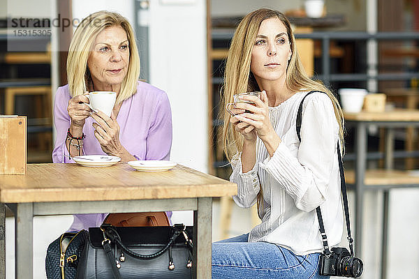 Reife Frau mit ihrer Tochter  die Kaffee und Tee trinkt und an einem Tisch im Freien in einem Café sitzt