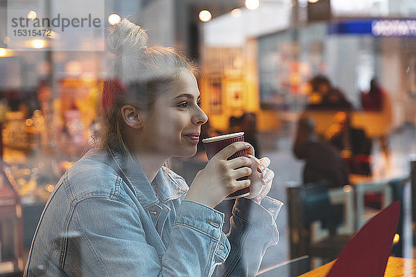 Junge Frau in einem Café  die einen Kaffee trinkt und genießt