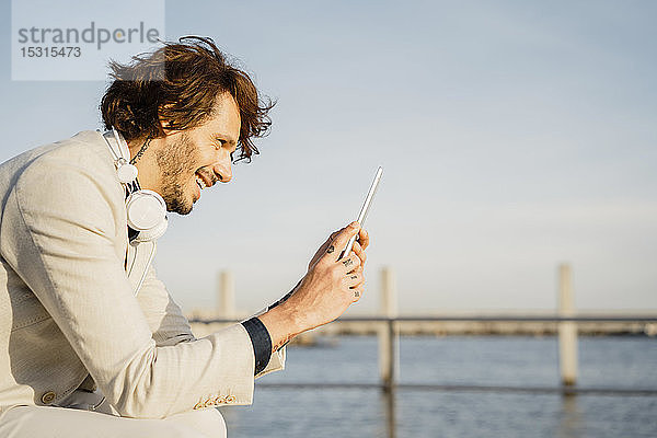 Lachender Geschäftsmann benutzt digitales Tablet im Freien