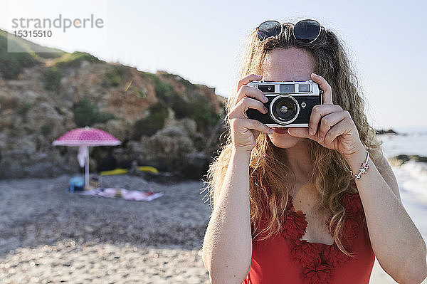 Junge Frau beim Fotografieren am Strand