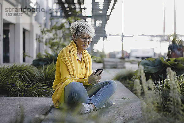 Reife Frau benutzt Smartphone im Freien