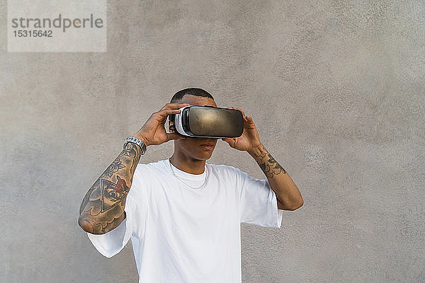 Tätowierter junger Mann mit Virtual-Reality-Brille schaut auf