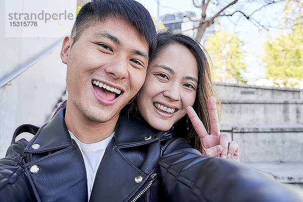 Porträt eines glücklichen jungen Paares beim Siegeszeichen
