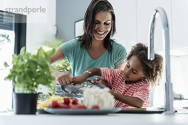 Glückliche Mutter und Tochter kochen gemeinsam in der Küche