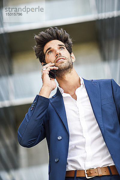 Geschäftsmann telefoniert vor einem Bürogebäude per Handy