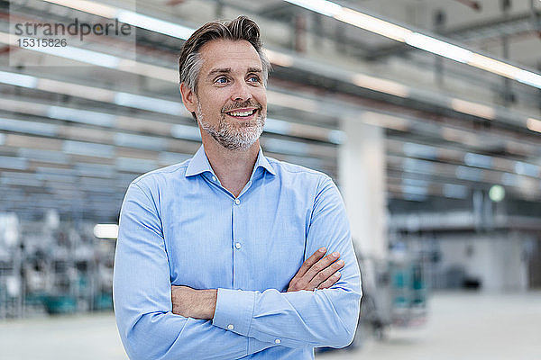 Porträt eines lächelnden Geschäftsmannes in einer Fabrikhalle