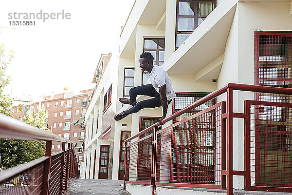 Junger Mann springt über einen Zaun in der Stadt