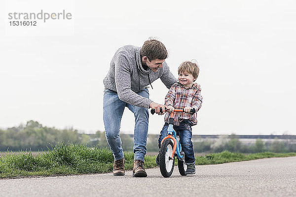 Vater bringt seinem Sohn das Fahrradfahren bei  im Freien