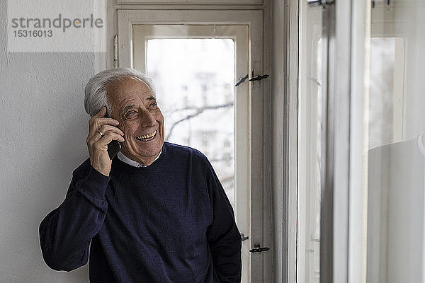 Glücklicher älterer Mann am Handy zu Hause