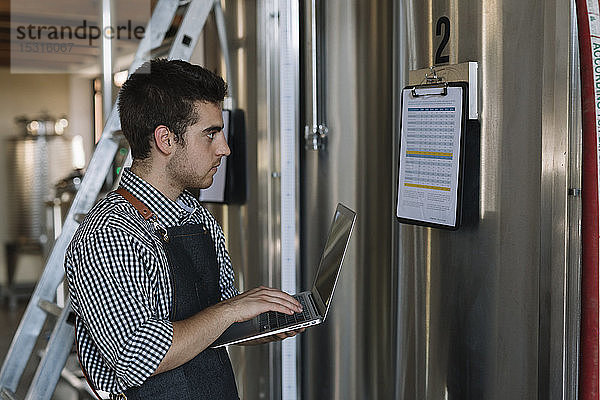Jungunternehmer arbeitet mit Laptop in einer Brauerei