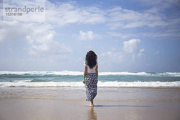 Rückenansicht einer Frau  die am Strand steht und auf das Meer schaut  Fuerteventura  Spanien