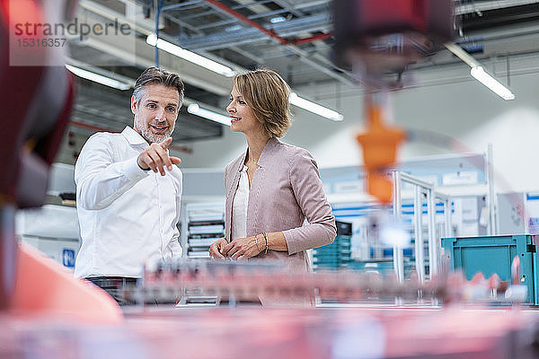 Geschäftsmann und Geschäftsfrau im Gespräch in einer modernen Fabrikhalle