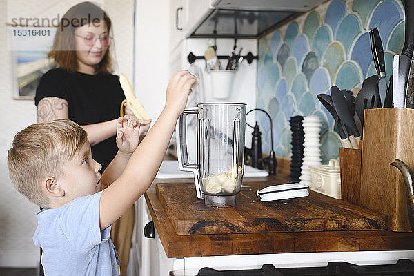 Mutter und Sohn kochen zu Hause in der Küche Bananenpfannkuchen