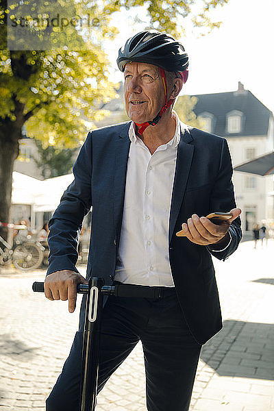 Älterer Mann mit E-Scooter in der Stadt mit Smartphone