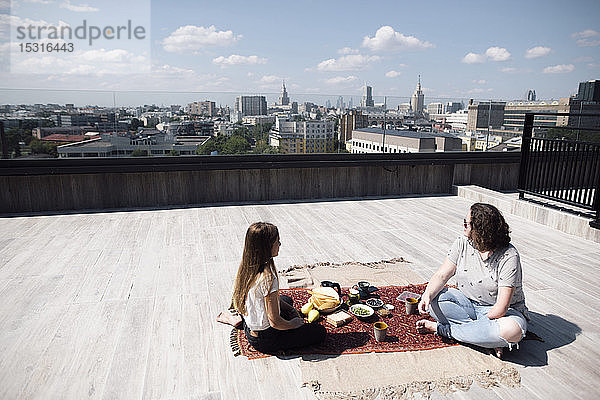 Frau mit Unterarmamputation und Mädchen mit gesunder Mahlzeit auf dem Dach
