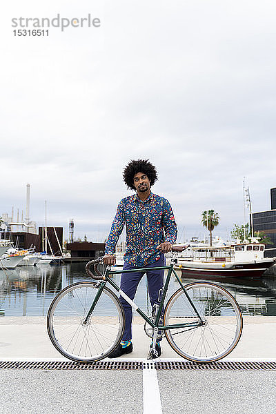 Porträt eines stilvollen Mannes mit Fahrrad am Yachthafen