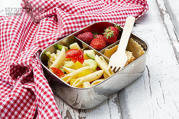 Nudelsalat  Erdbeeren und Cracker in Lunchbox auf Holztisch