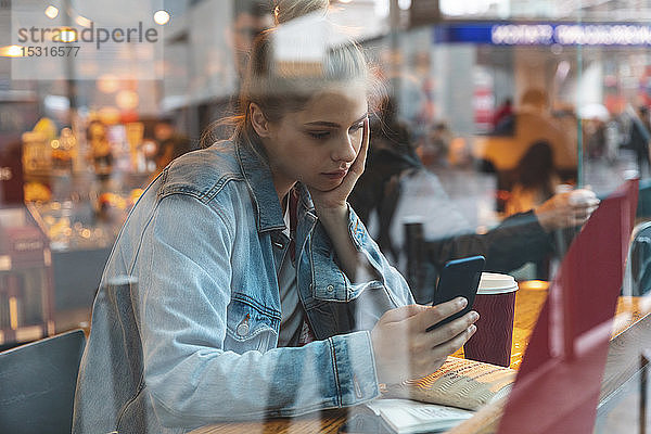 Junge Frau in einem Café mit einem Smartphone