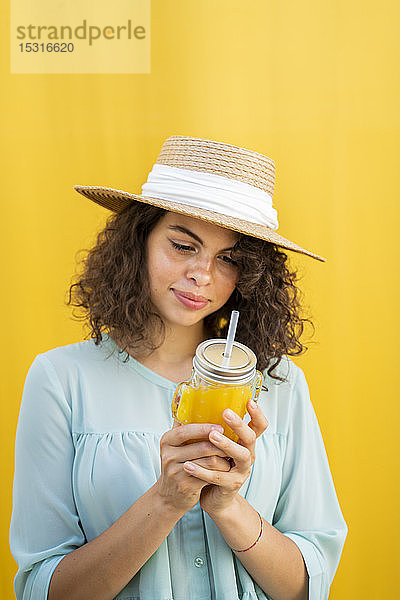 Bildnis einer Frau mit Strohhut  Saft trinkend  gelber Hintergrund