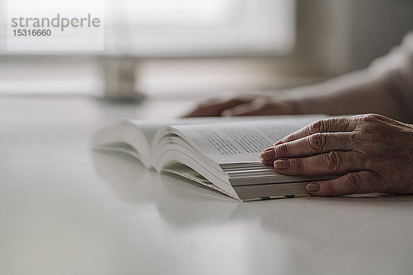 Nahaufnahme einer älteren Frau  die ein Buch auf dem Tisch liest