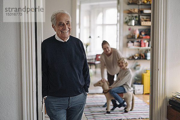 Glücklicher Großvater mit Frau und Enkel zu Hause im Hintergrund