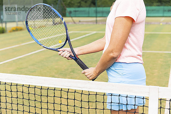 Tennisspielerin hält den Schläger auf dem Rasenplatz
