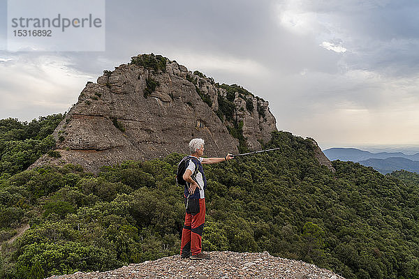 Wanderer zeigt mit Wanderstock  auf Aussichtspunkt stehend