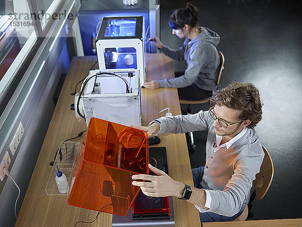 Zwei am Tisch sitzende Techniker mit 3D-Drucker