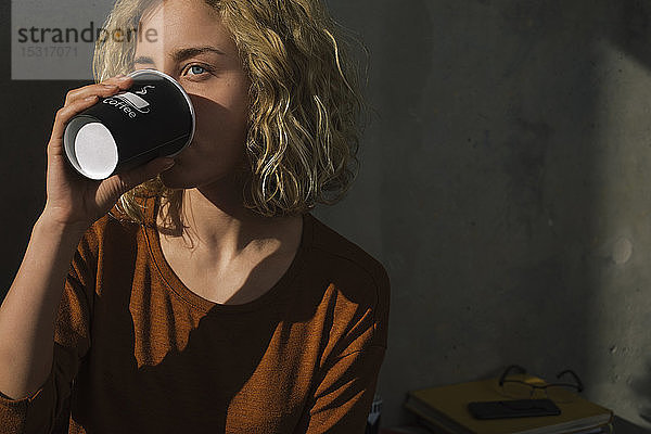 Blonde junge Frau trinkt Kaffee für zu Hause