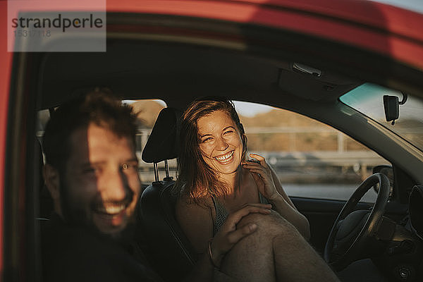 Glückliches Paar auf einer Autoreise mit Blick aus dem Autofenster