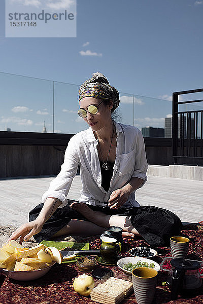Stilvolle Frau mit Sonnenbrille beim gesunden Essen auf dem Dach