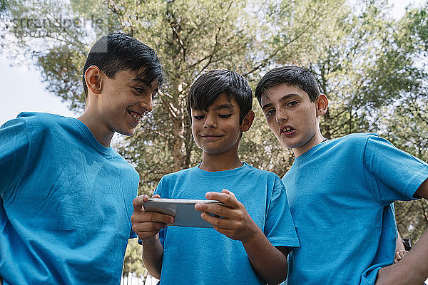 Drei Jungen in blauen T-Shirts mit Smartphone