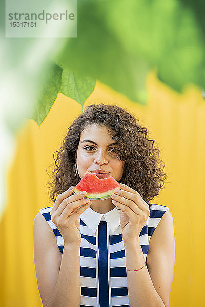 Porträt einer Frau  die eine Wassermelone isst  gelber Hintergrund