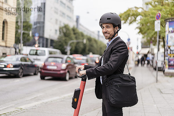 Lächelnder Geschäftsmann mit E-Scooter in der Stadt