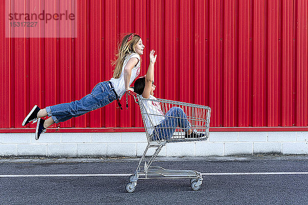 Schwestern mit Einkaufswagen vor roter Wand