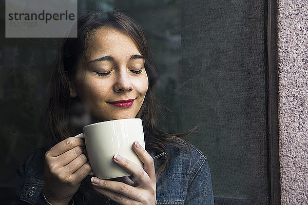Junge Frau in Café mit Tasse Kaffee und geschlossenen Augen